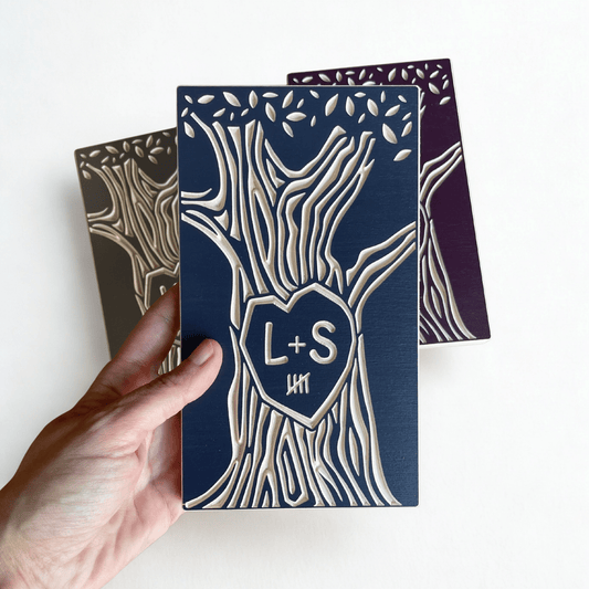 Hand holding a personalized wooden anniversary gift with 'L+S' initials, 5 year marks, and tree design on a white background