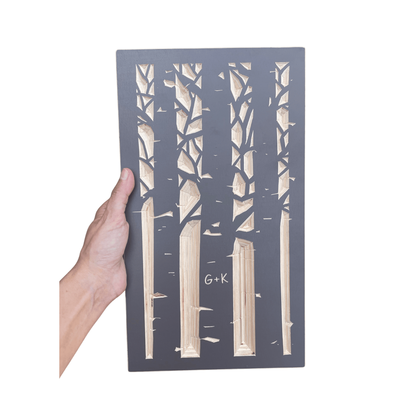 Hand holding a decorative panel with aspen tree cutout design on a white background