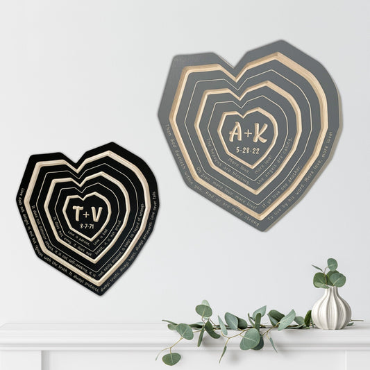 Two heart-shaped wooden plaques with personalized engravings, one larger and one smaller, placed on a white surface with a small decoration to the side.