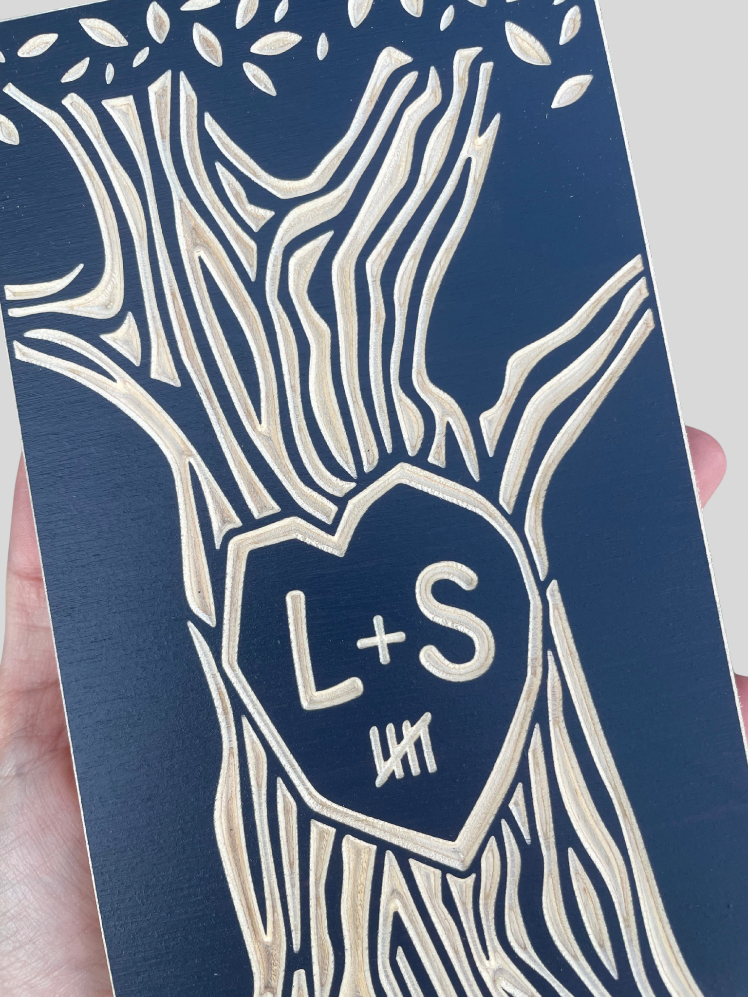 Close-up view of  5 year anniversary tree design and heart-shape with initials 'L+S' on a blue background