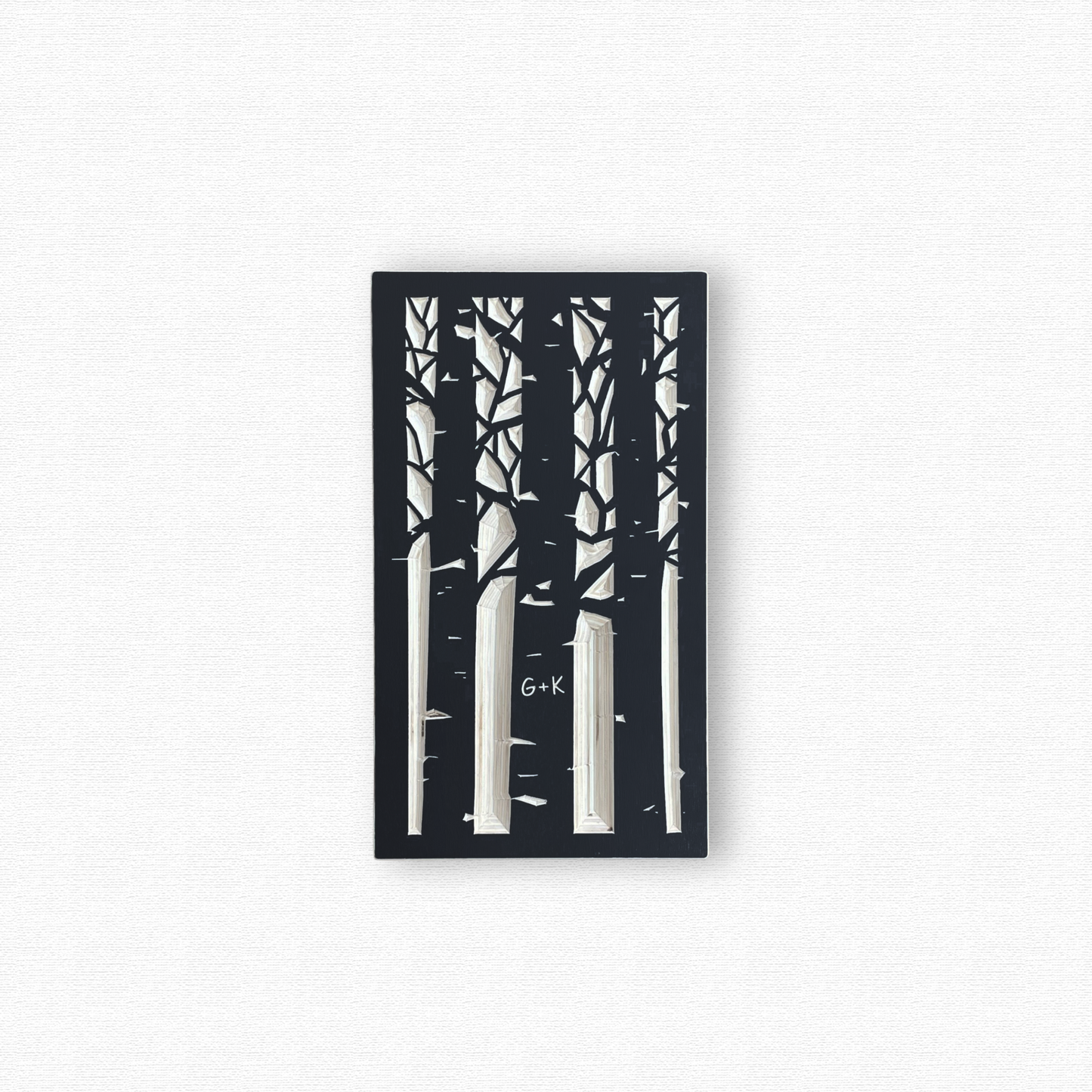 Decorative wooden wall art with black silhouettes of an aspen forest with a couple's initials carved in a trunk. Shown in black finish on white background.