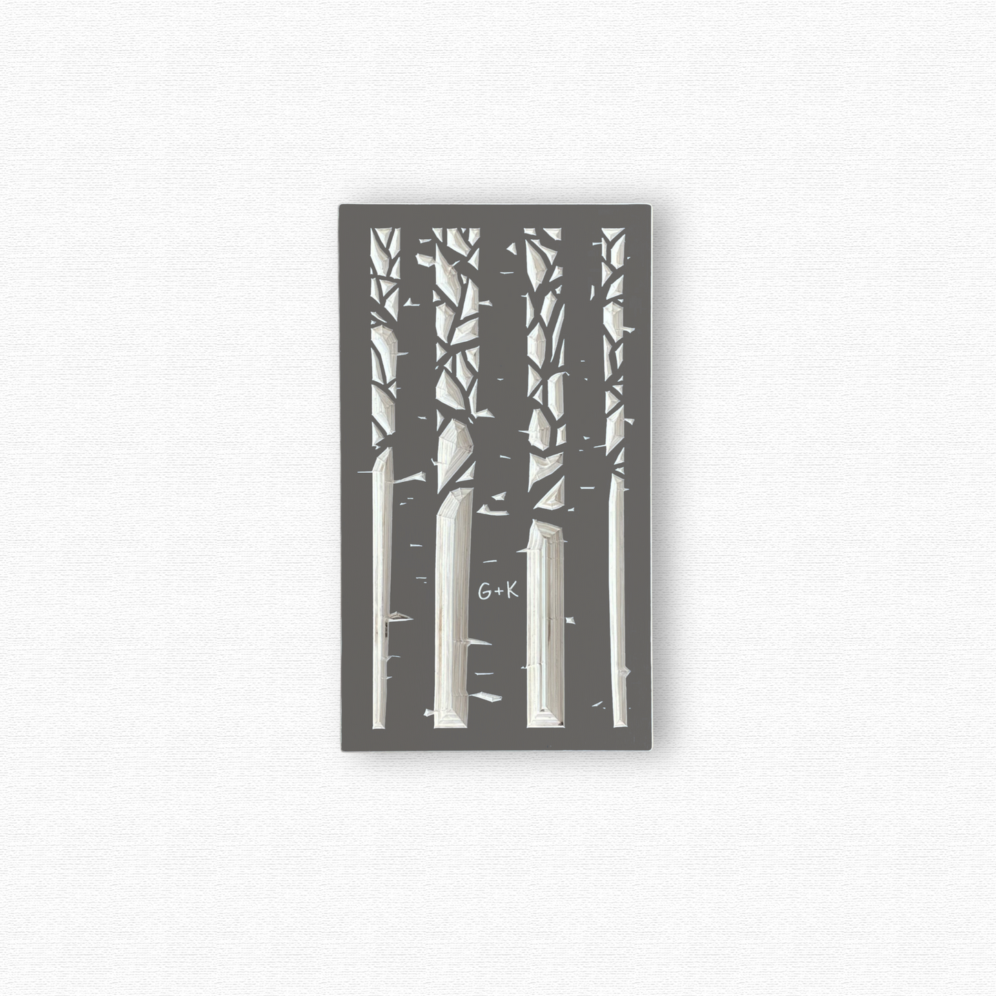 Decorative wooden wall art with black silhouettes of an aspen forest with a couple's initials carved in a trunk. Shown in taupe gray finish on white background.
