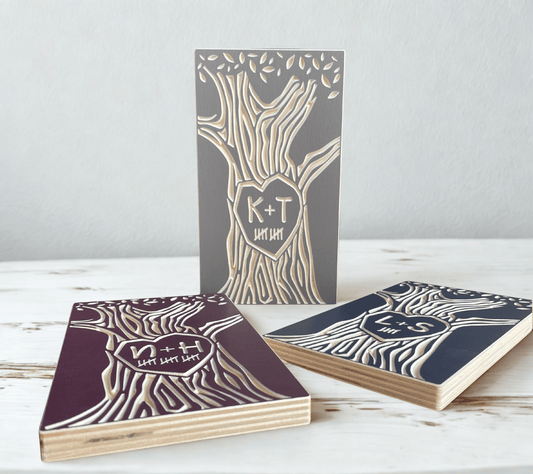 Three wooden desk accessories with tree designs and initials on a white surface