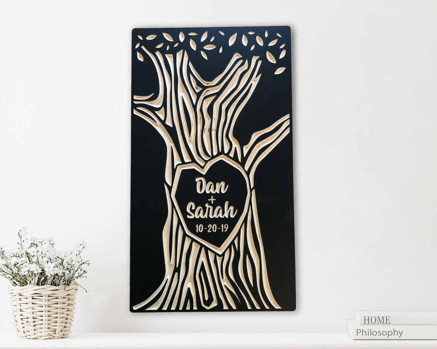 Solid wood panel, painted black. Tree trunk with a heart shape in the center and canopy of leaves is carved as the design. Personalized with two names and a special date, like a couple carving their names on a tree.