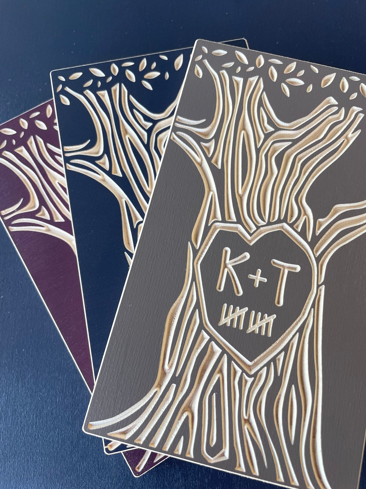 Decorative couple art with intricate tree carving and custom initials on a dark blue background