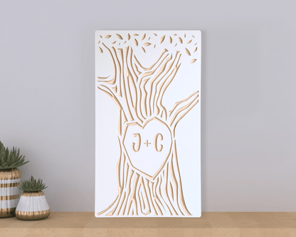 Decorative wall art with tree design and a couple of initials on a plain background