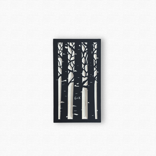 Decorative wooden wall art with black silhouettes of an aspen forest with a couple's initials carved in a trunk. Shown in black finish on white background.