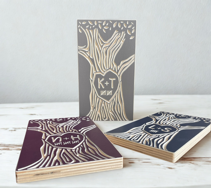 Three wooden desk accessories with tree designs and initials on a white surface