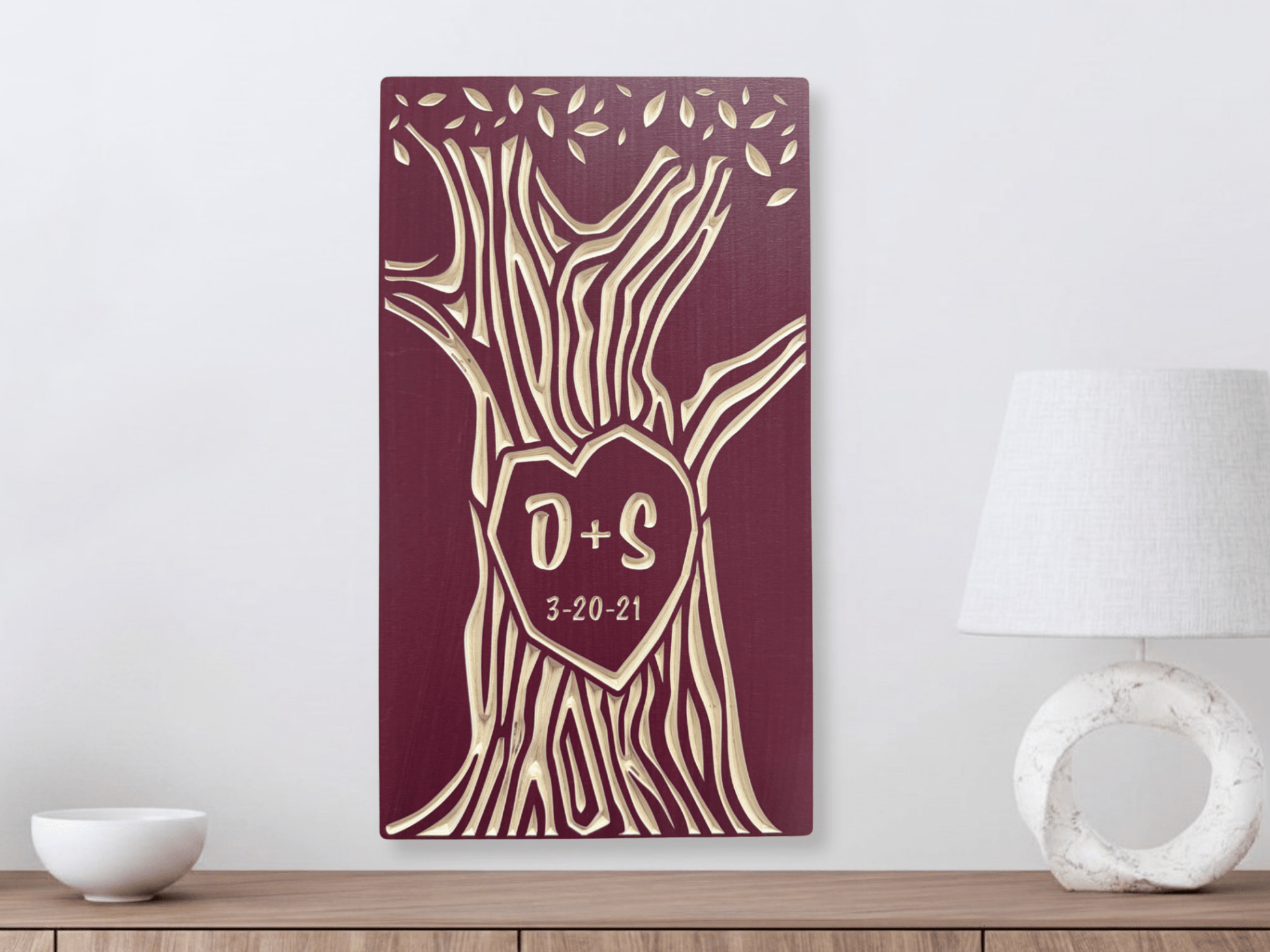 Decorative wall art with tree design and initials on a wooden surface.