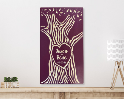 Personalized wood wall art with names carved in tree trunk shown in burgundy finish, hanging on a white wall above a wooden shelf. 