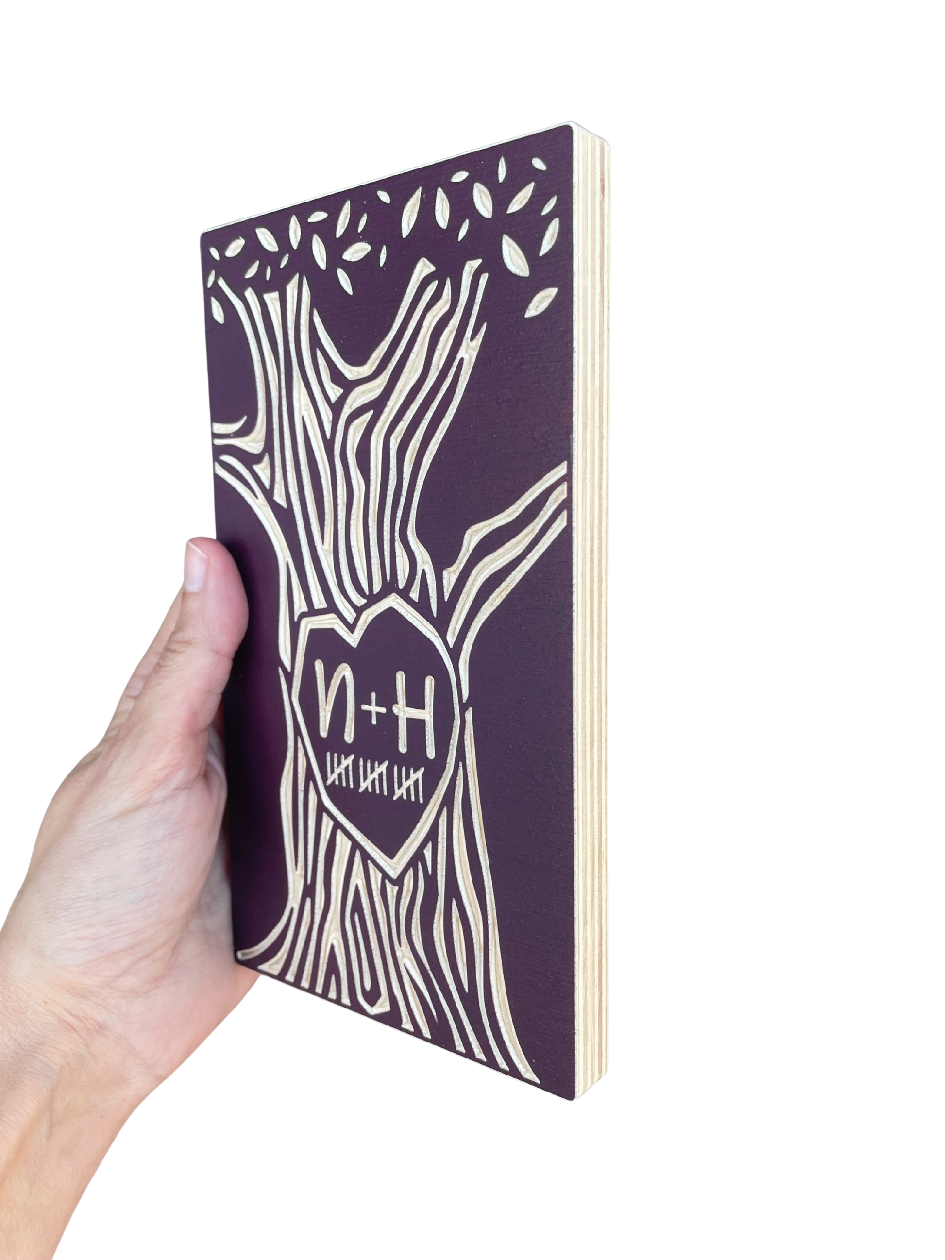 Hand holding a burgundy 15 year anniversary tree on a white background