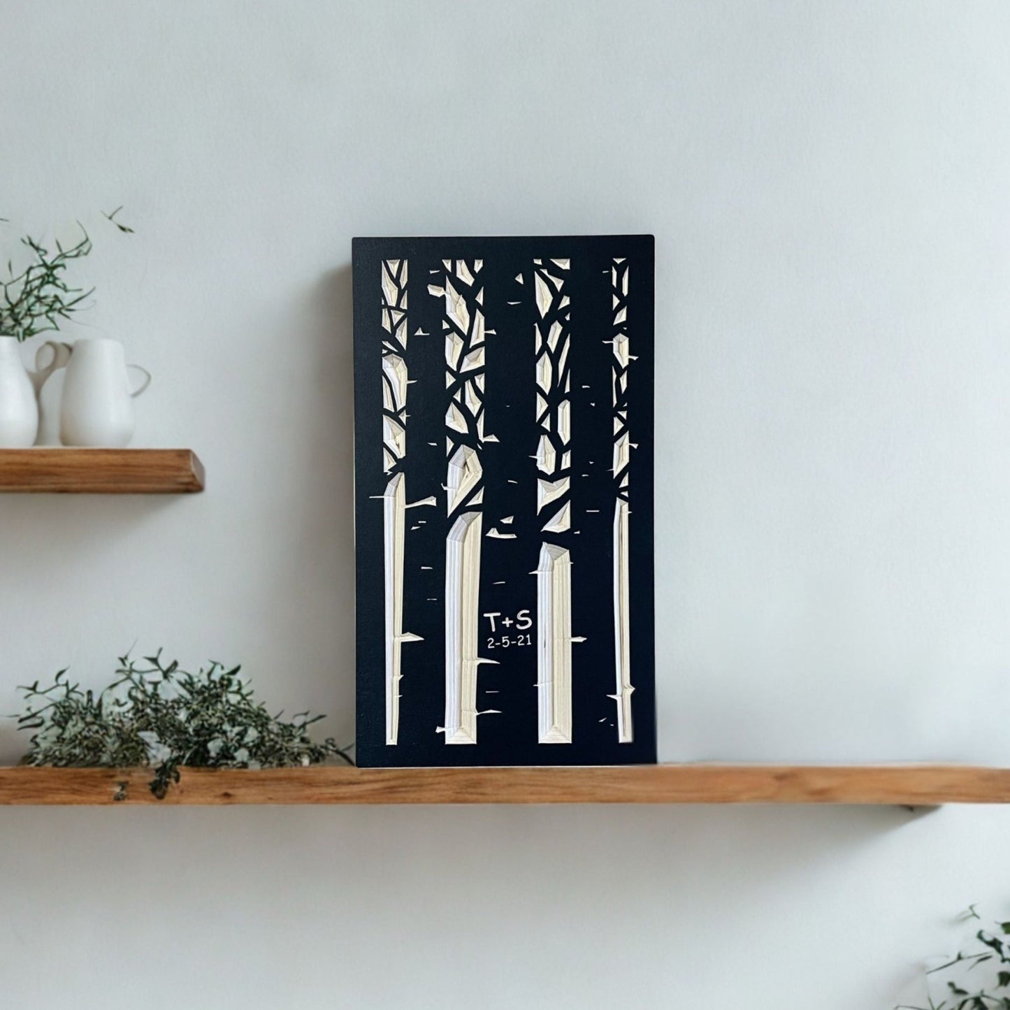 Wooden shelf with decorative items and a carved wooden artwork of trees on a white wall.