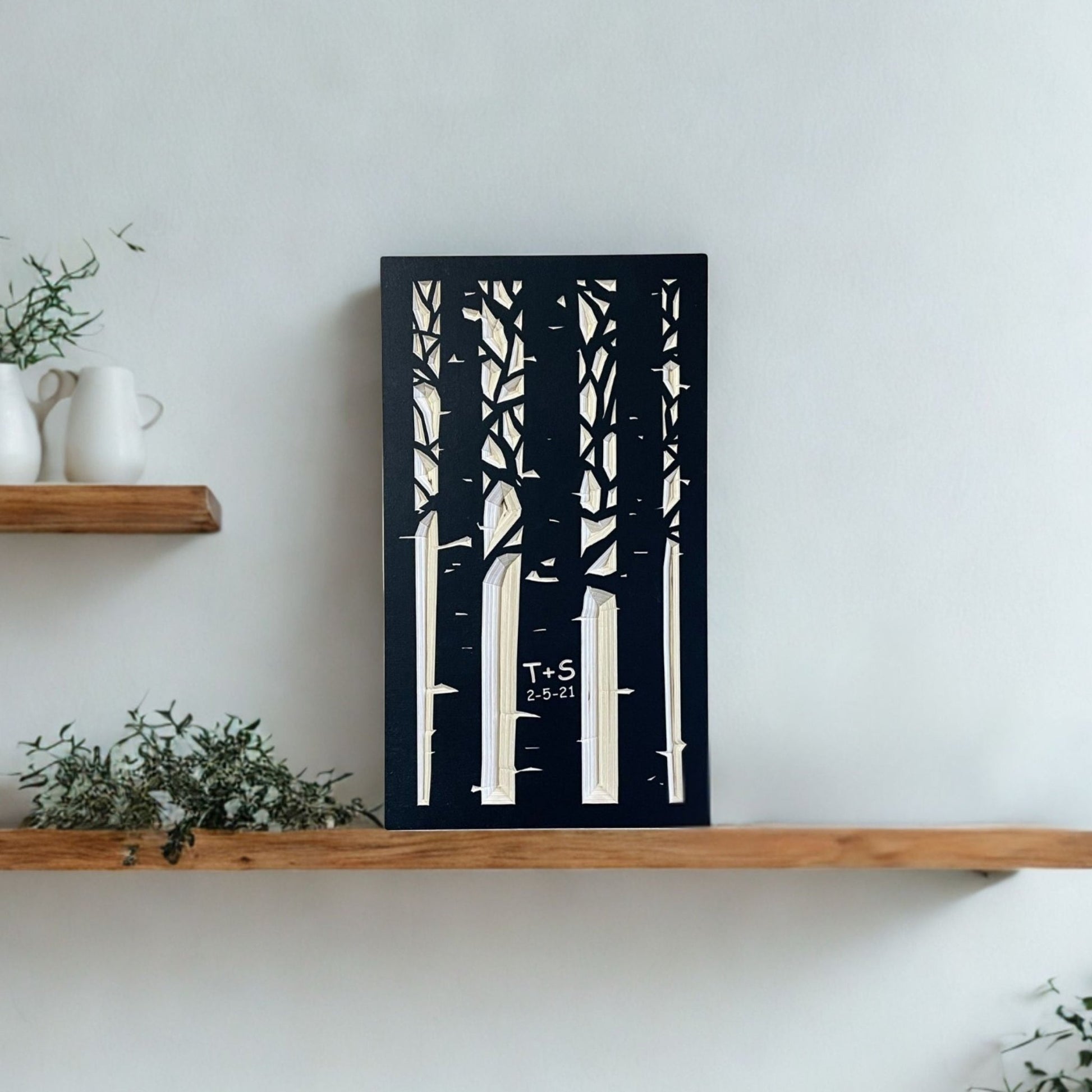 Wooden shelf with decorative items and a carved wooden artwork of trees on a white wall.