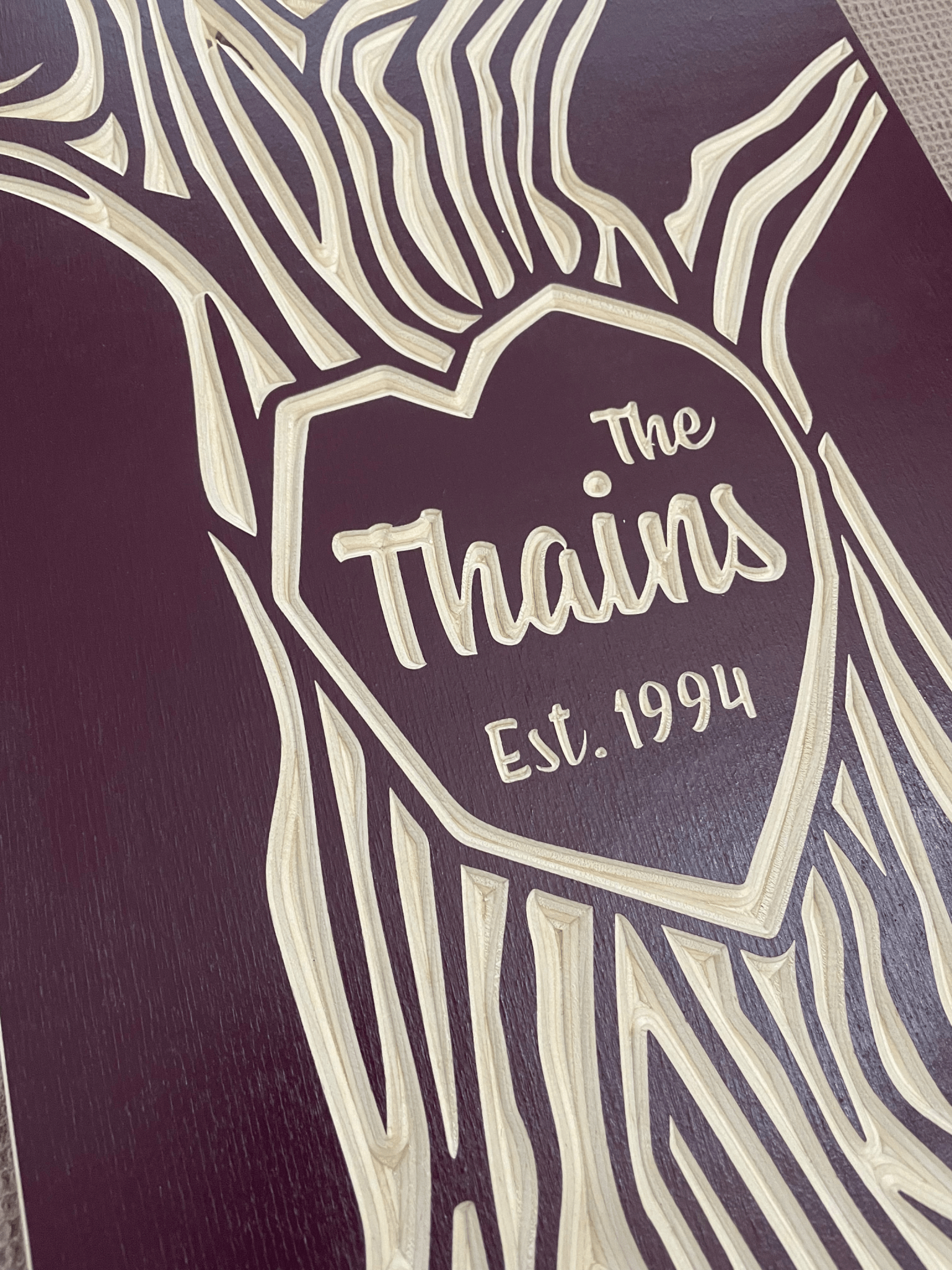 Closeup view of family name carved in tree design, burgundy color option.