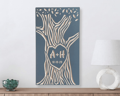Decorative wall art with tree design and personalized initials on a gray background, hanging above a wooden surface.