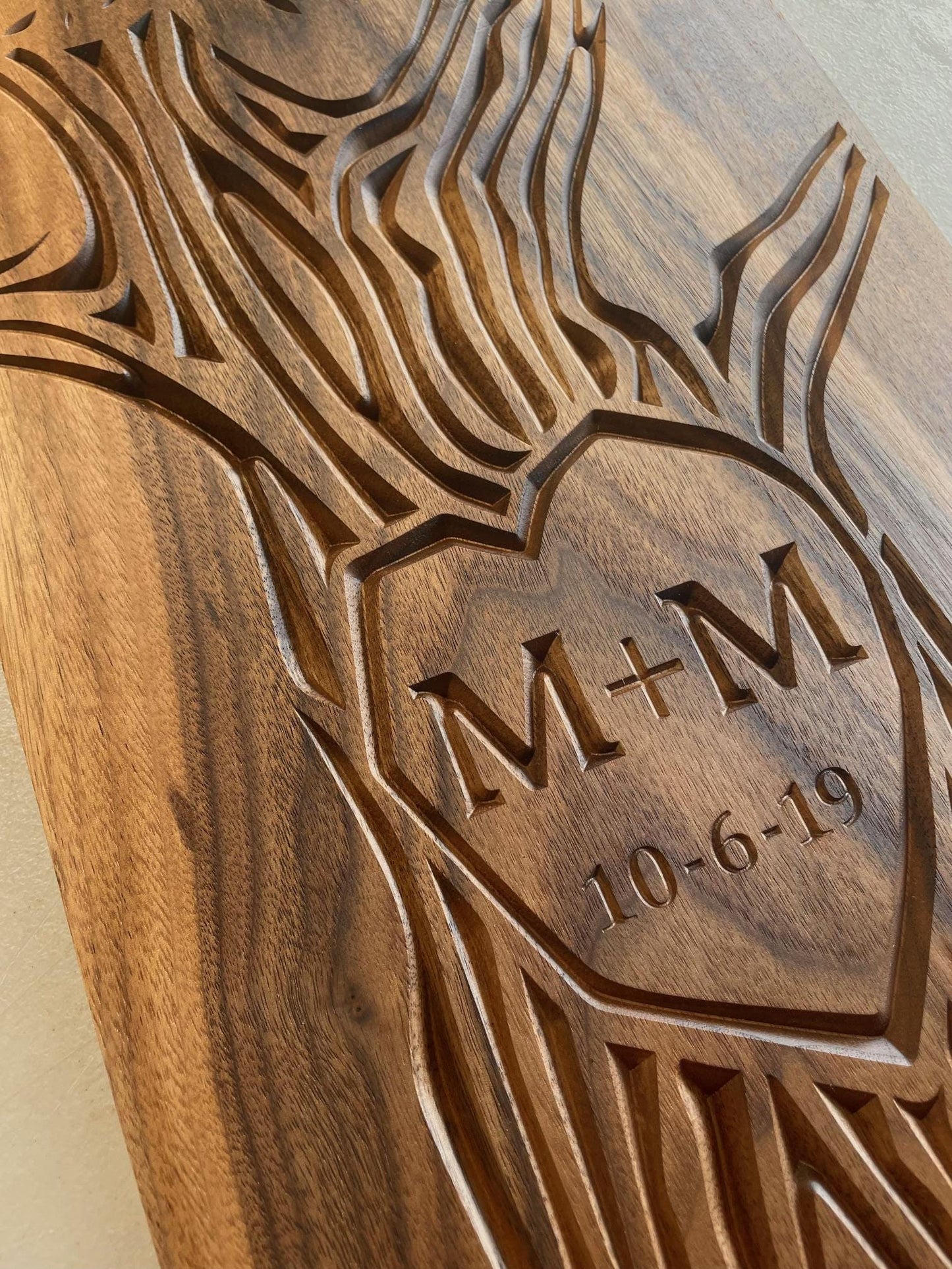 Detailed view of carved wall art with initials and wedding date carved into the trunk of a tree design. Artwork is carved on a solid walnut wood panel