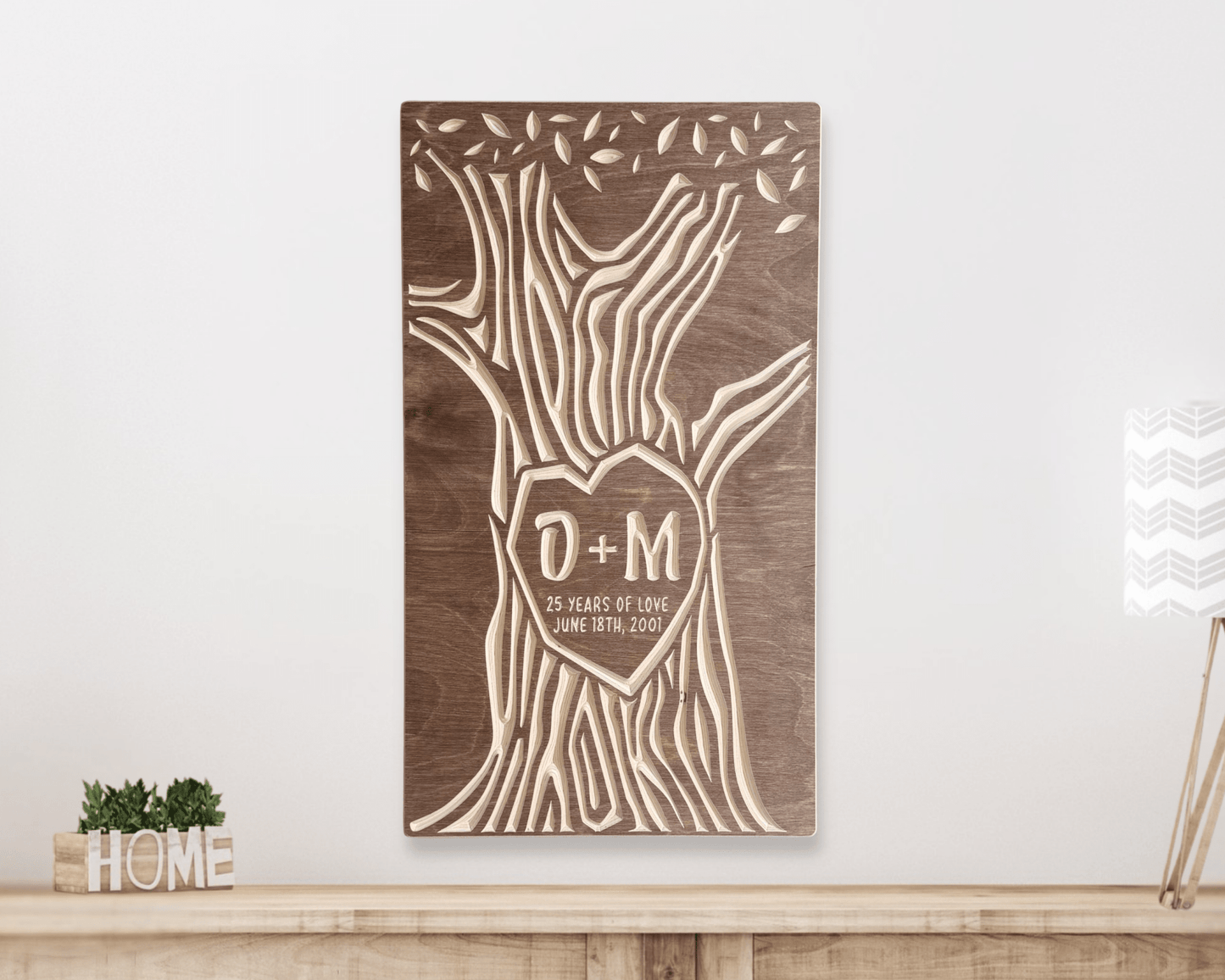 Wooden wall art with tree design customized with 25th anniversary text on a white wall.