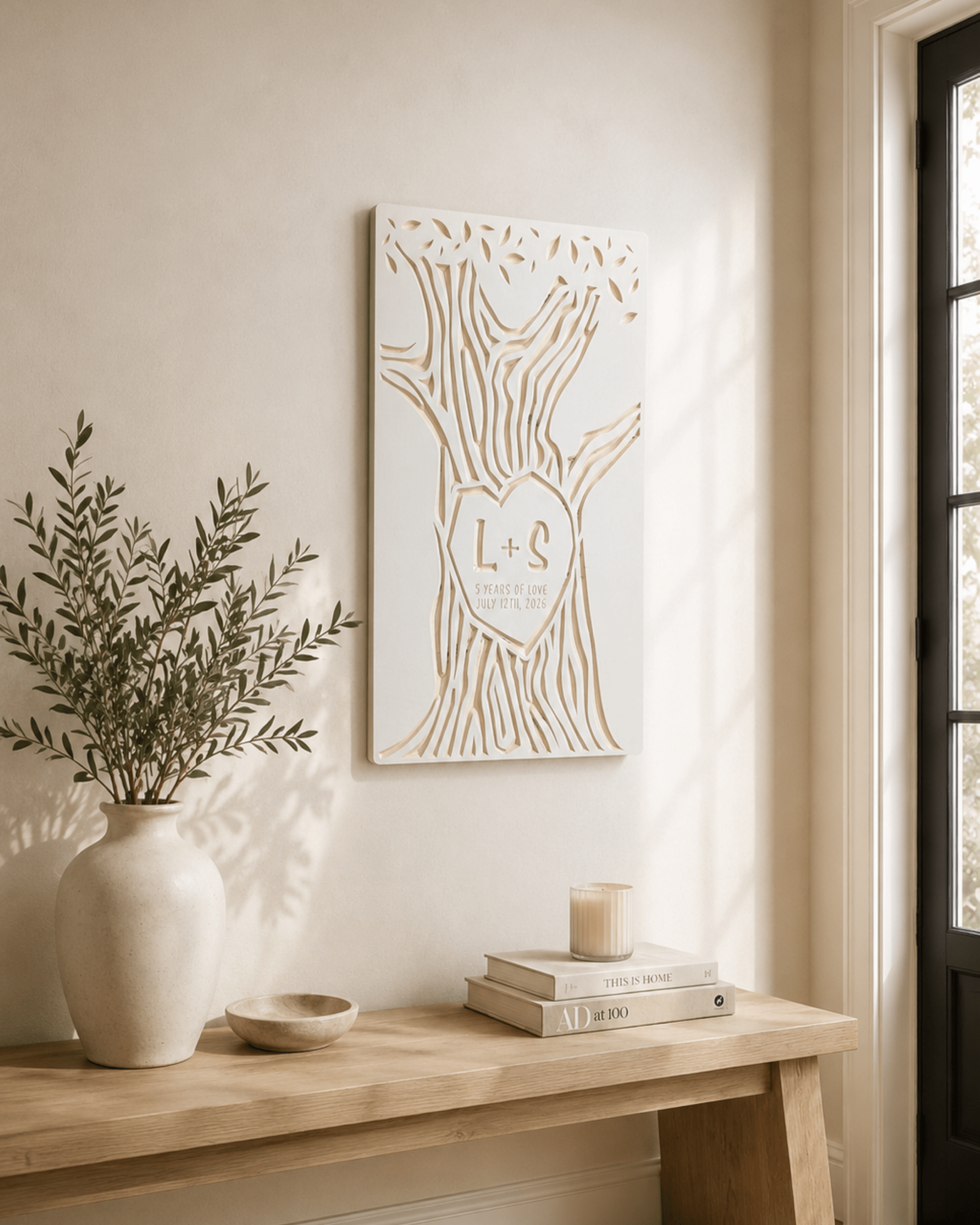 A personalized wooden tree wall art piece with a heart-shaped cutout containing the initials 'L+S', displayed on a beige wall above a light wood bench in a styled home interior.